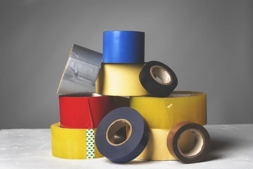 A variety of tape rolls including duct tape, electrical tape, masking tape, painters tape; all stacked